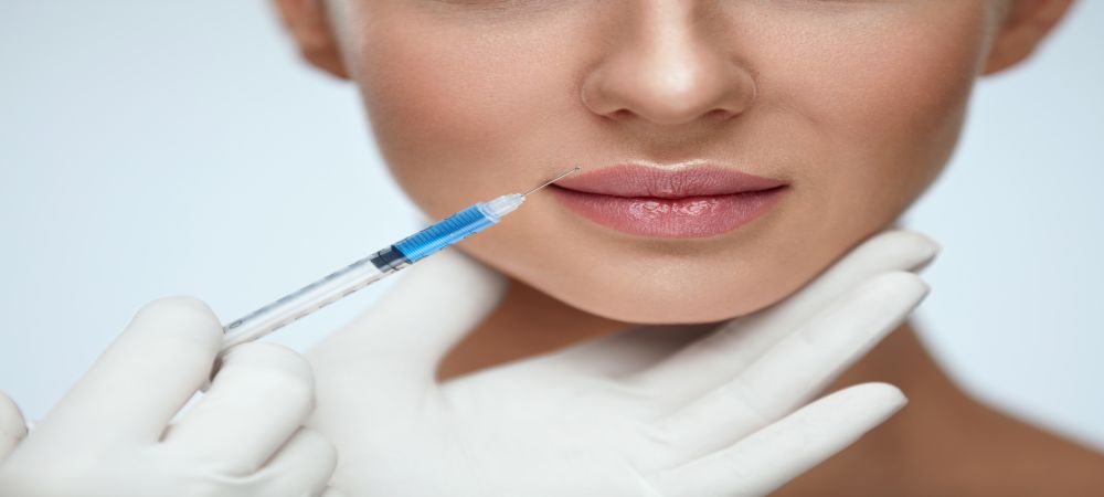 Aesthetician holding needle to persons lips