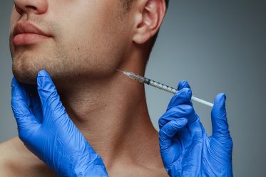 Close-up portrait of young man isolated on grey studio background Belkyra filler for double chin removal